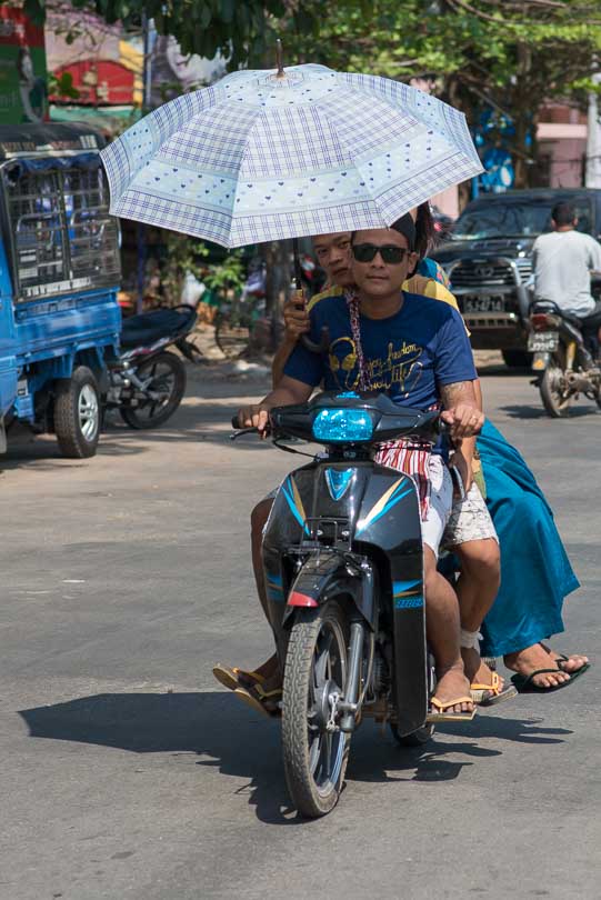 Menschen auf einem Mopedmit Sonnenschirm in Myanmar